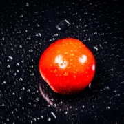 Kuvassa on tomaatti mustalla pöydällä.