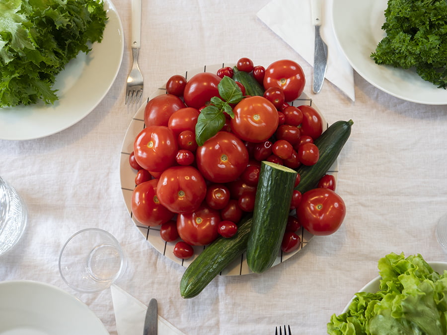 Kuvassa on lautasella paljon tomaattia, kurkka ja salaatteja.