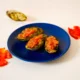 Kuvassa on sinisellä lautasella kolme pan con tomatea. Kuvan tausta on kermansävyinen.